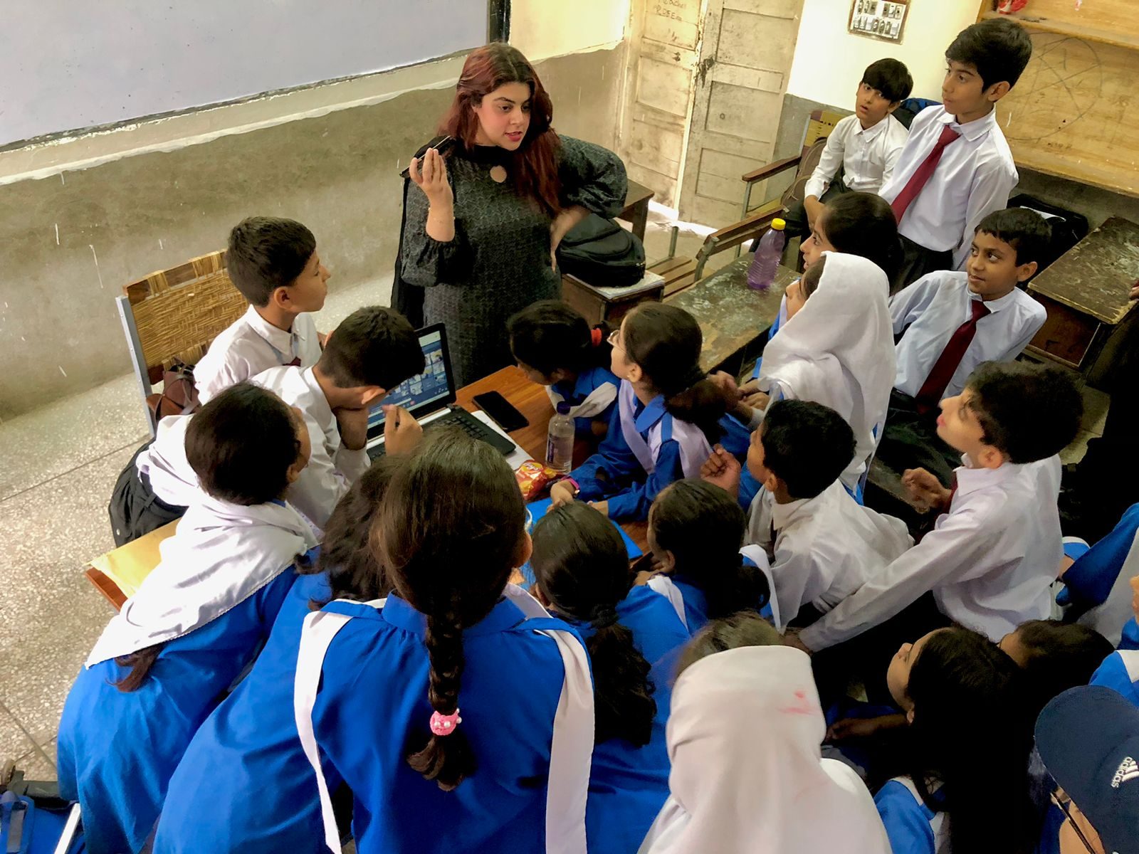 Students gathering around a laptop during a global classroom connection